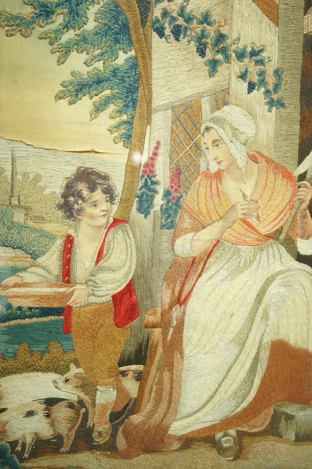 Two Regency silk embroidered and painted figurative panels. Both mother and child scences. One an intimate farmyard scene, embroidered with mother and child, flowers, a cat and pigs. The other of a mother helping her chi
